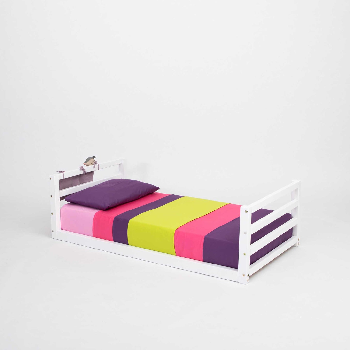 A long-lasting Sweet Home From Wood 2-in-1 kids' bed with a horizontal rail headboard and footboard, with colorful sheets and a white frame, that can grow with the child.