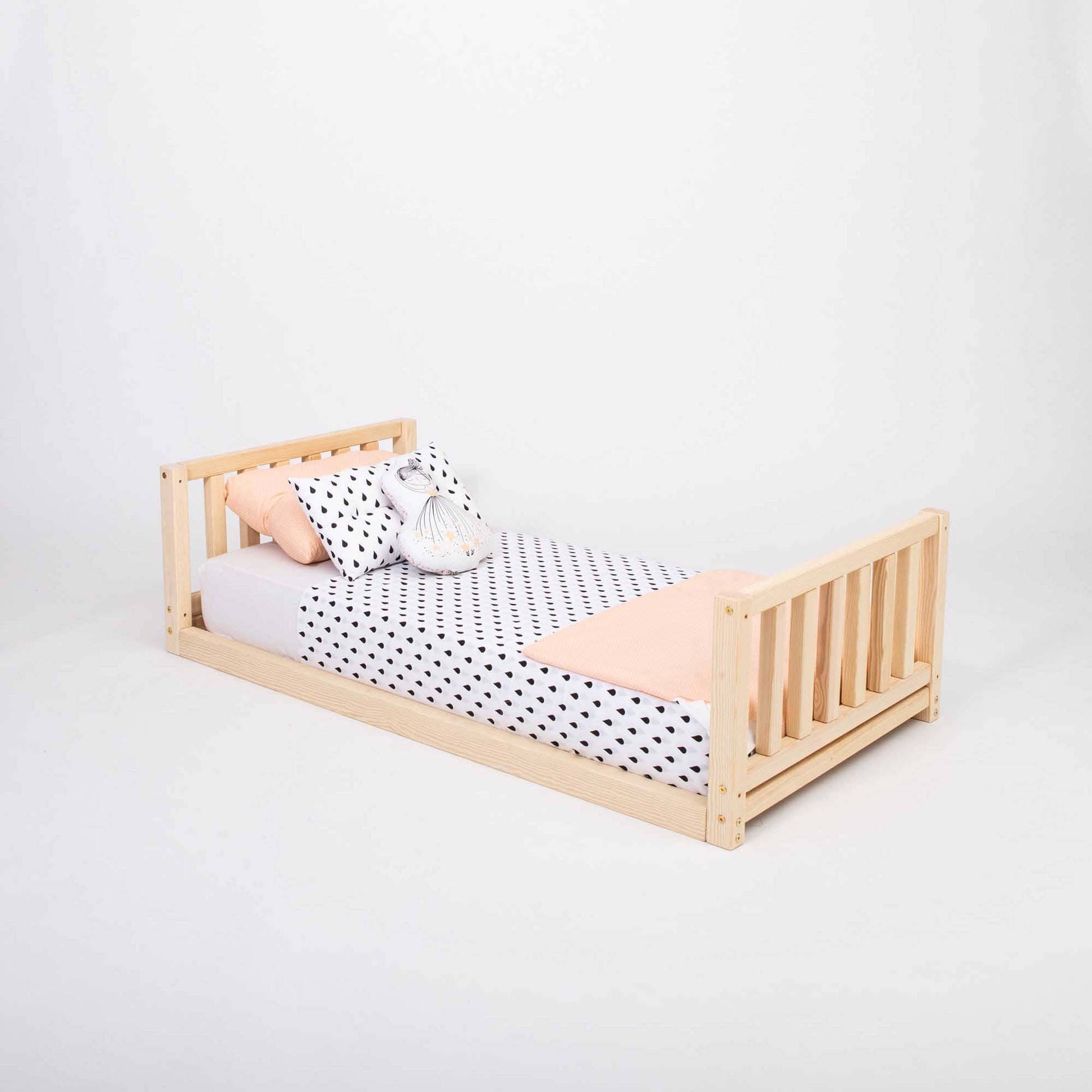 A 2-in-1 kid's bed on legs with a vertical rail headboard and footboard with polka dot bedding made of solid pine or birch wood.