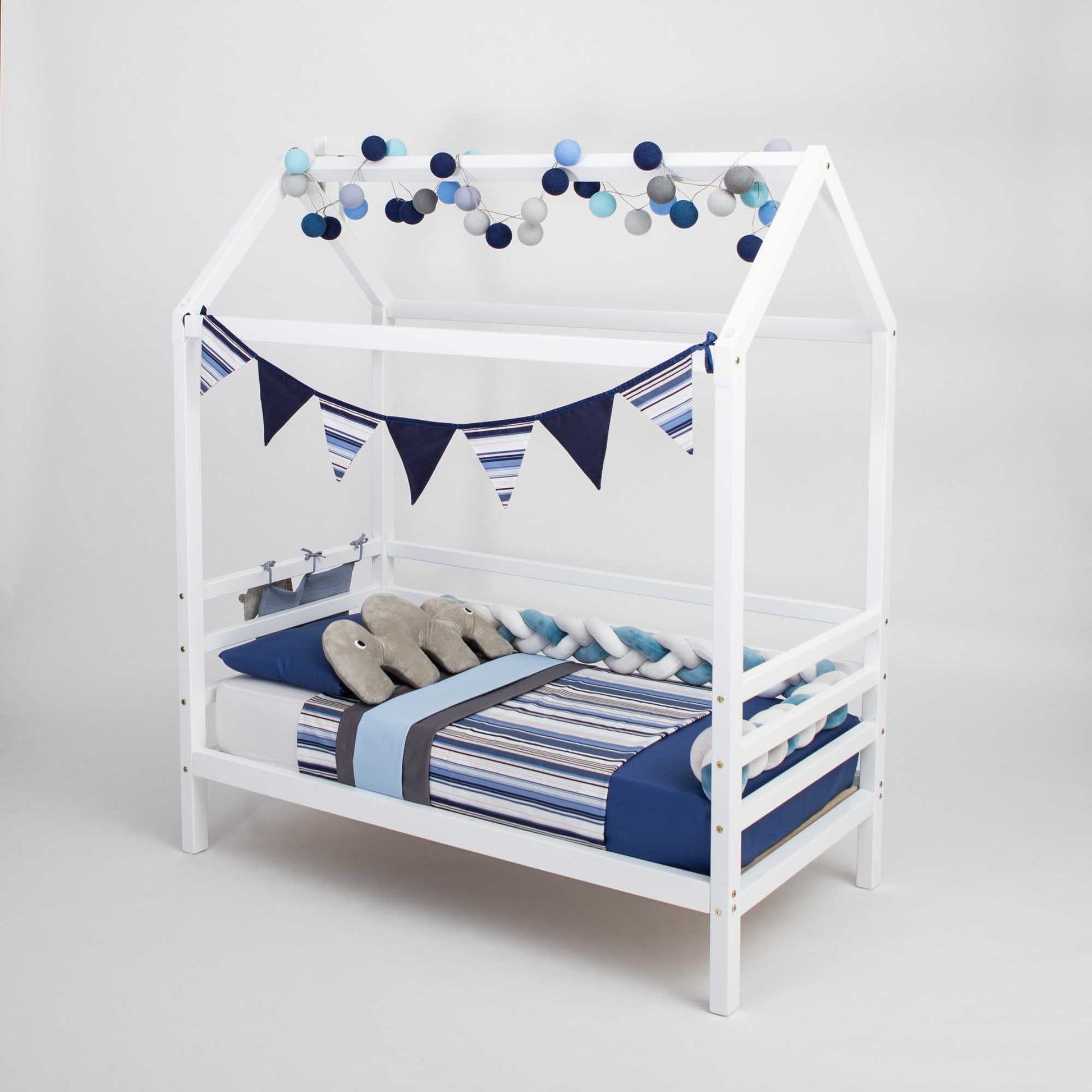 A blue and white striped children's house bed on legs with 3-sided rails and bunting.