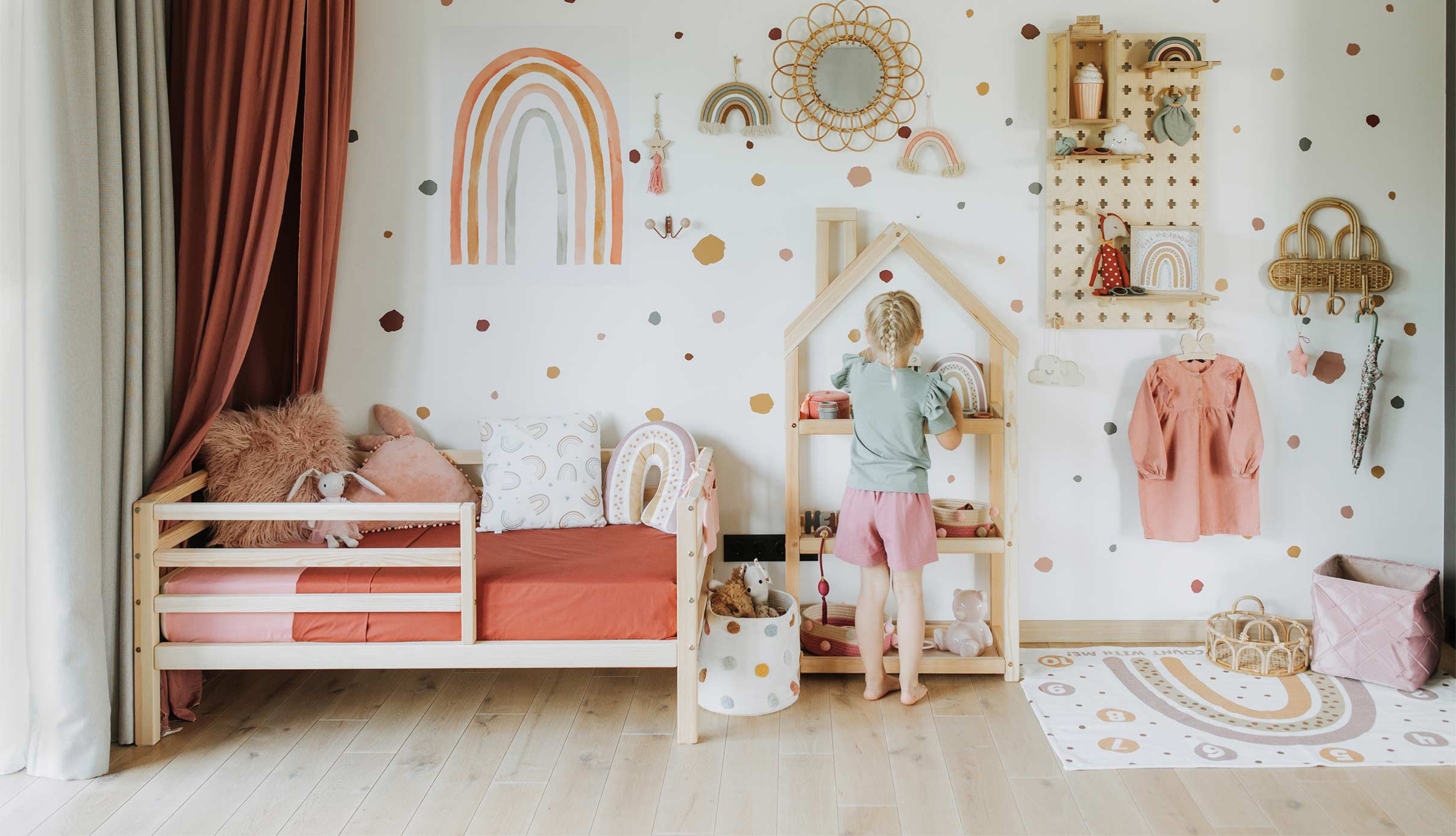 A child's room with a bed, shelves, and a rainbow wall.