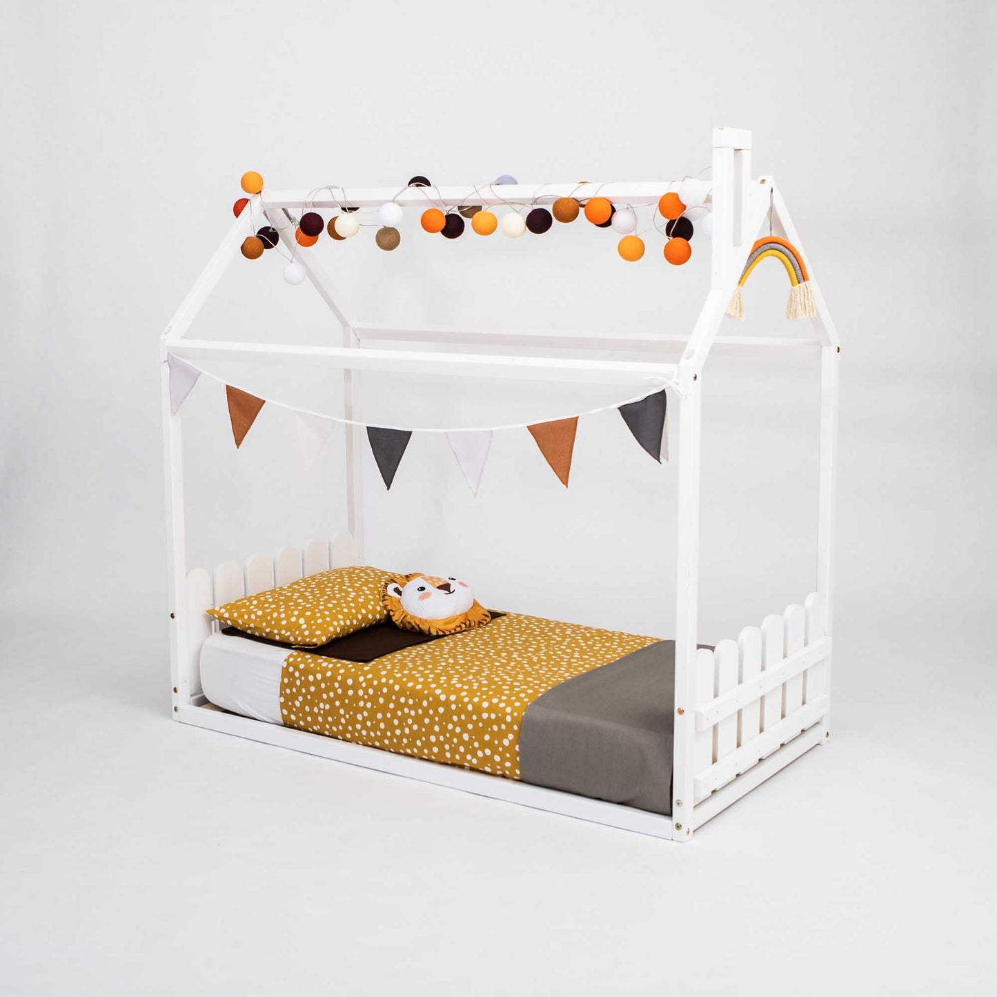 A low platform Montessori house-frame bed with a picket fence headboard and footboard, perfect as a montessori house bed for toddlers.