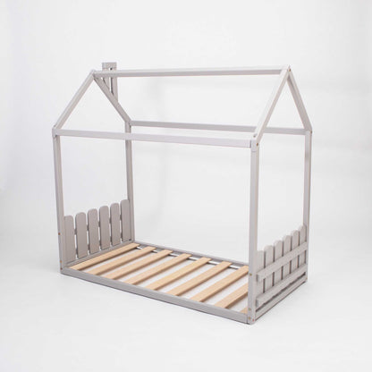 A Montessori-inspired Montessori house-frame bed with a picket fence headboard and footboard.