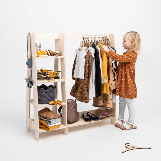 A little girl exploring Sweet Home From Wood's children's wardrobe and dress-up clothing rack.