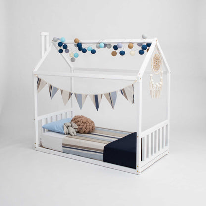 A Sweet Home From Wood Toddler house bed with a headboard and footboard adorned with a blue canopy, creating a peaceful sleep haven.