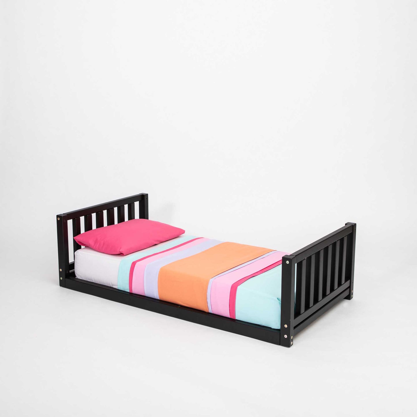 A 2-in-1 kid's bed on legs with a vertical rail headboard and footboard, with a colorful bed sheet.