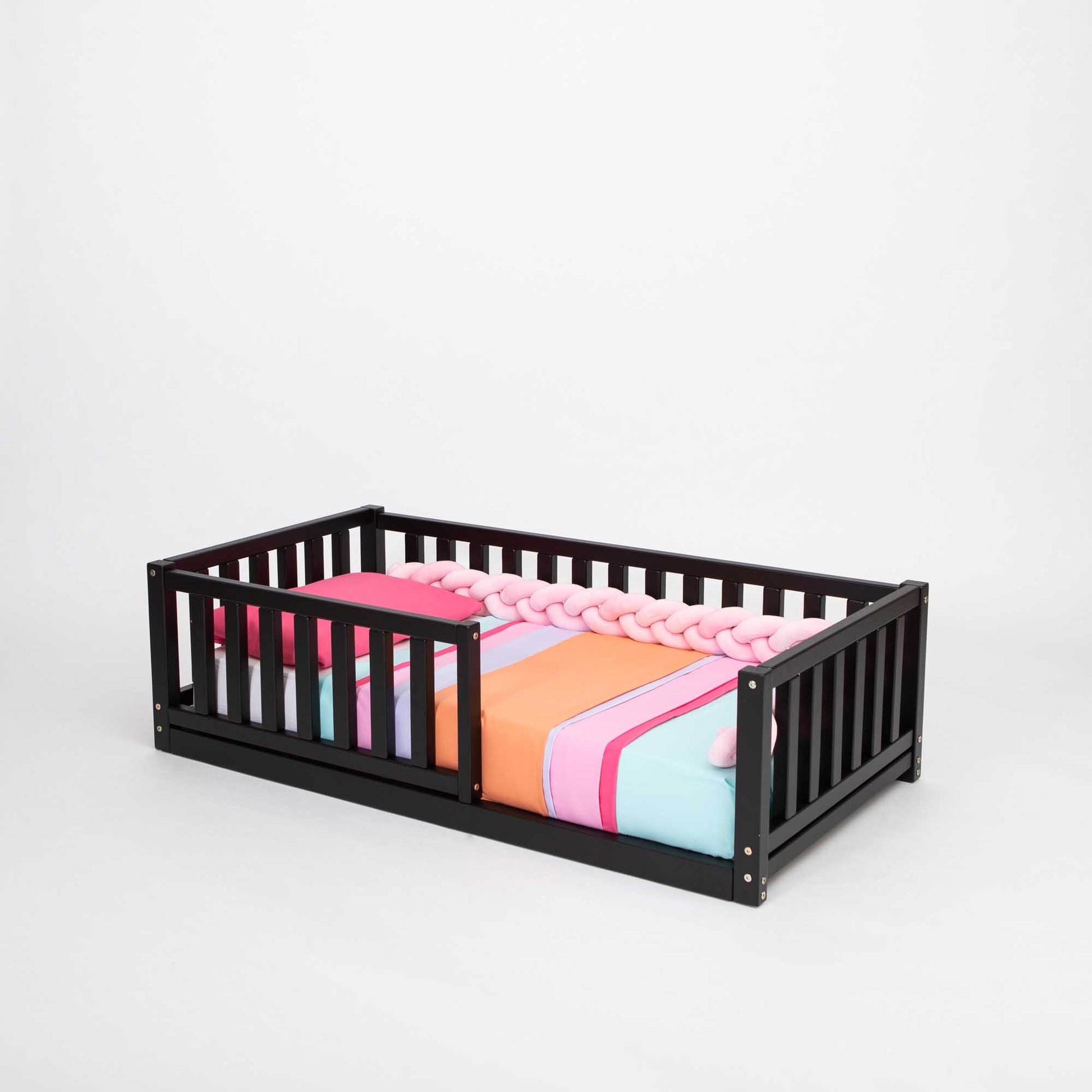 A long-lasting Sweet Home From Wood 2-in-1 toddler bed on legs with a vertical rail fence, made from solid pine, featuring a colorful blanket on top.