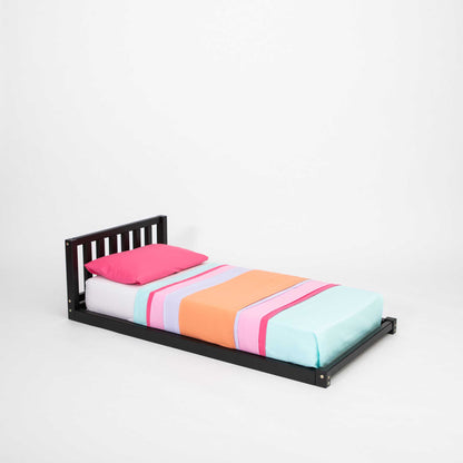 A toddler bed with a headboard and a colorful bed sheet.