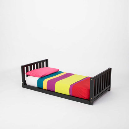 A black Sweet Home From Wood toddler bed with colorful striped sheets, perfect for boys or girls.