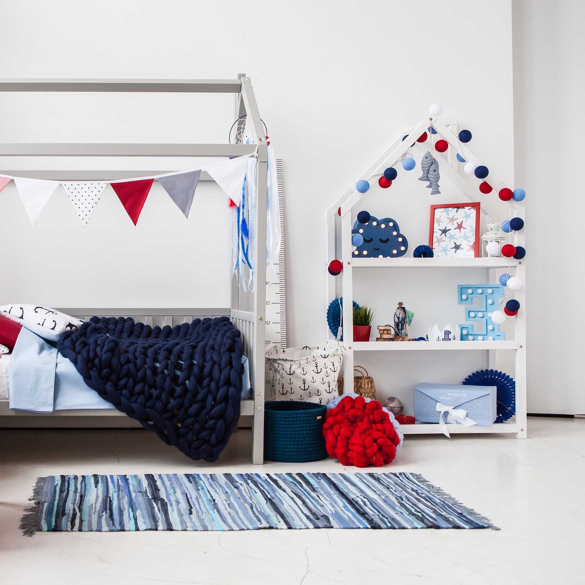 A boy's bedroom with a blue and red canopy bed featuring Sweet Home From Wood's house-shaped Montessori shelf for kids.