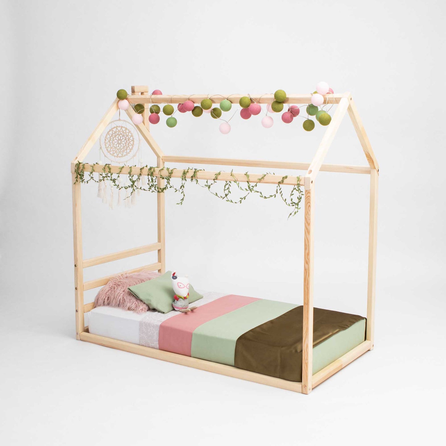 A Children's house bed with a horizontal headboard and cozy sleep haven featuring pom poms from Sweet Home From Wood.