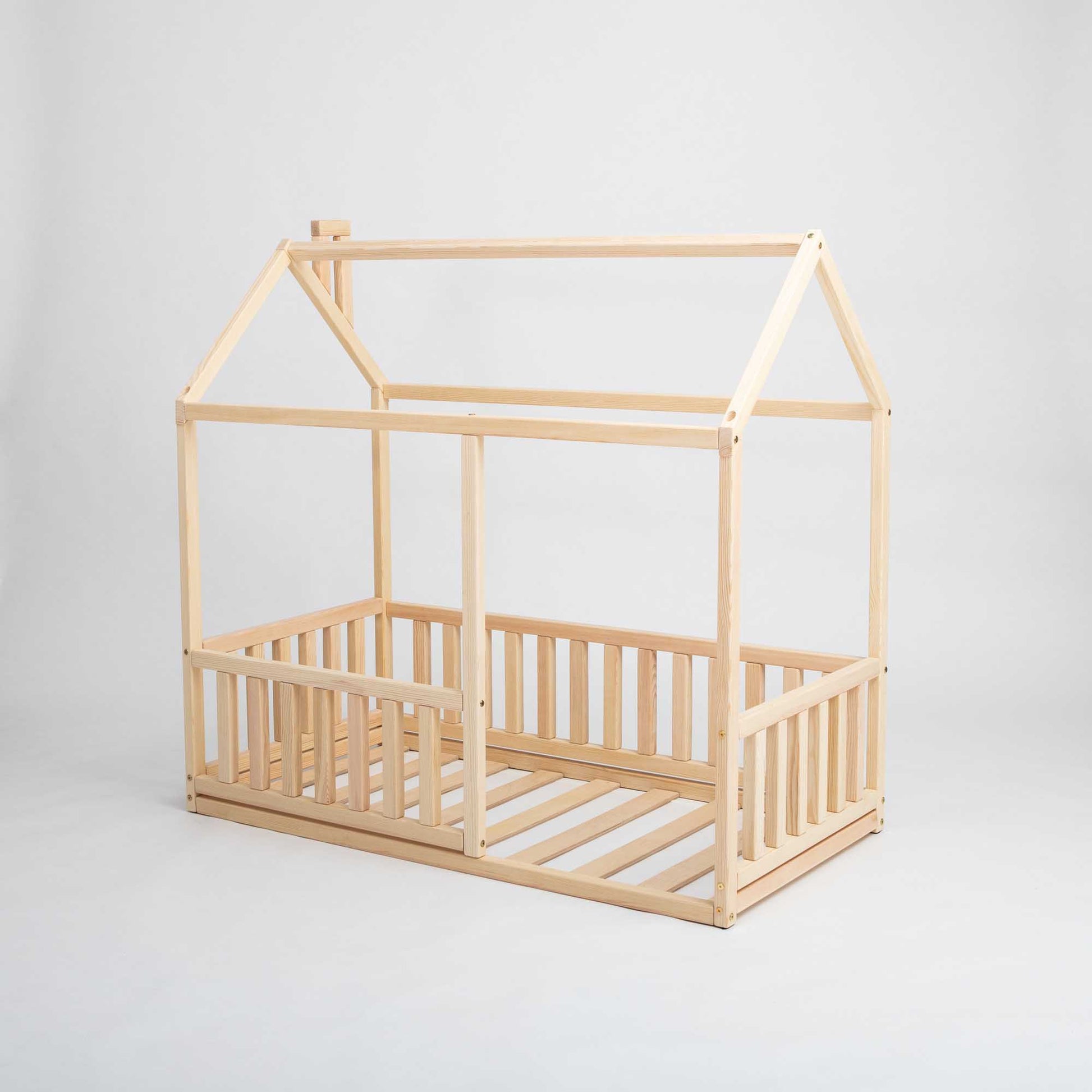 A cozy Sweet Home From Wood Montessori floor house bed with rails and a slatted roof.