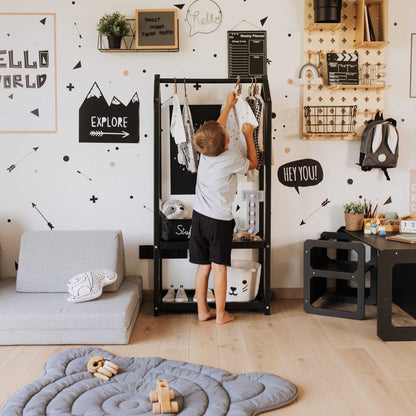 A child's room with an open Montessori wardrobe from Sweet Home From Wood featuring a black and white theme.
