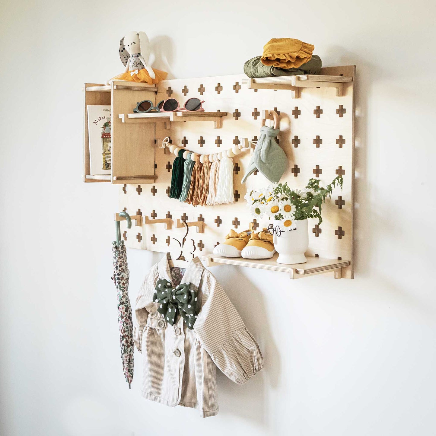 A Sweet HOME from wood Floating Shelves Pegboard with clothes hanging on its open storage shelves.