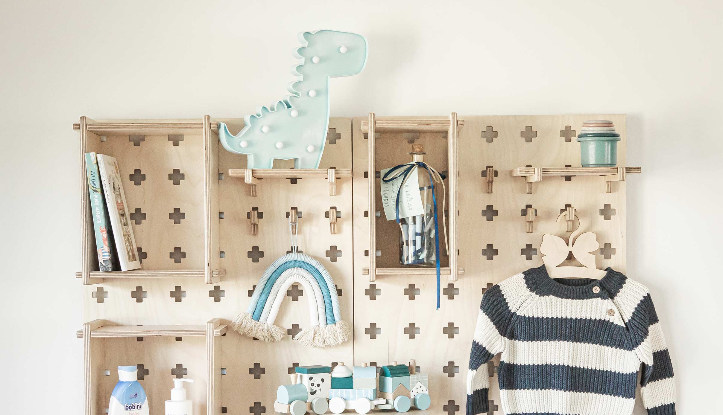 A child's room with clothes, toys, and a wooden shelf.