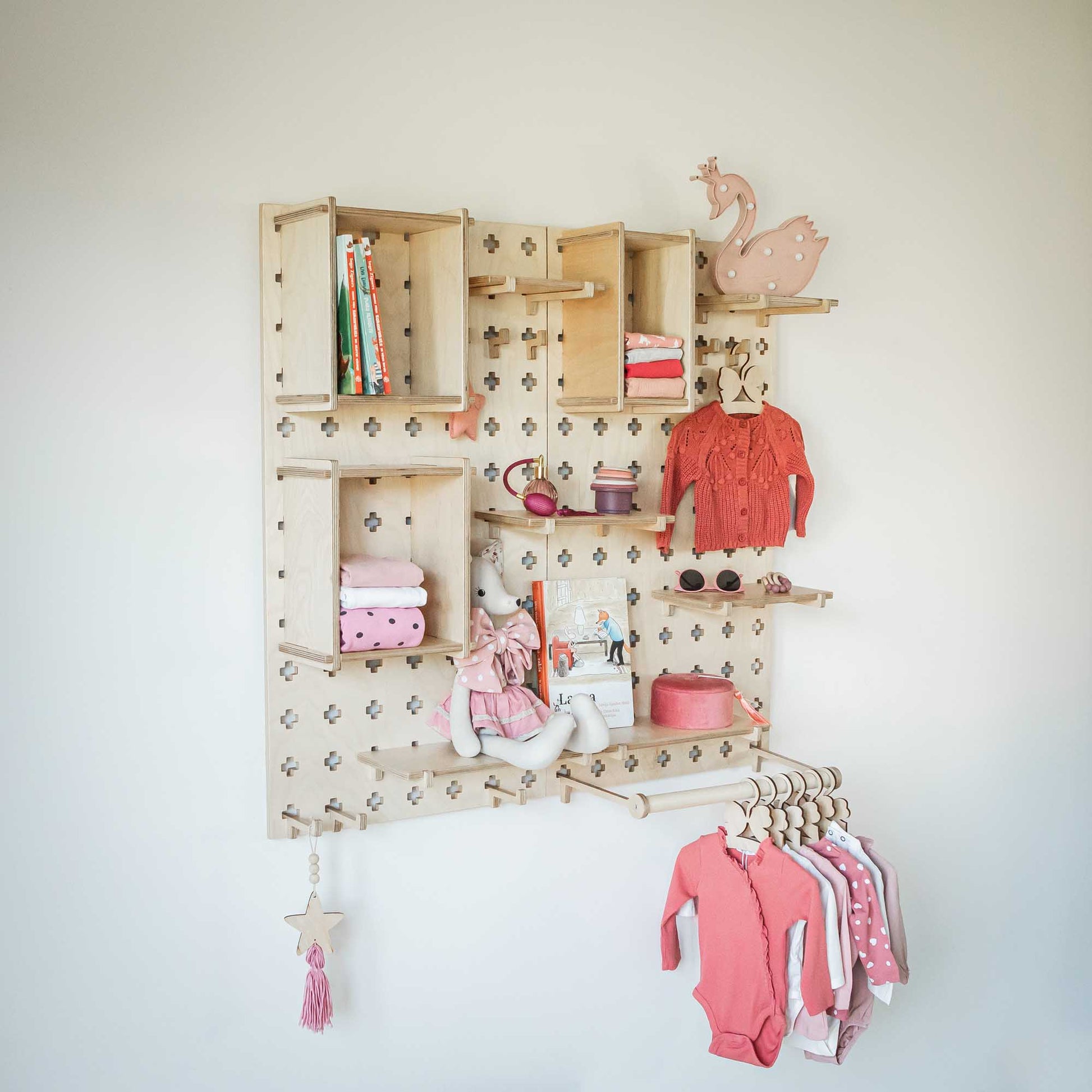 A baby's room with a pegboard wall featuring Sweet HOME from wood's Large Pegboard Shelf with Clothes Hanger.