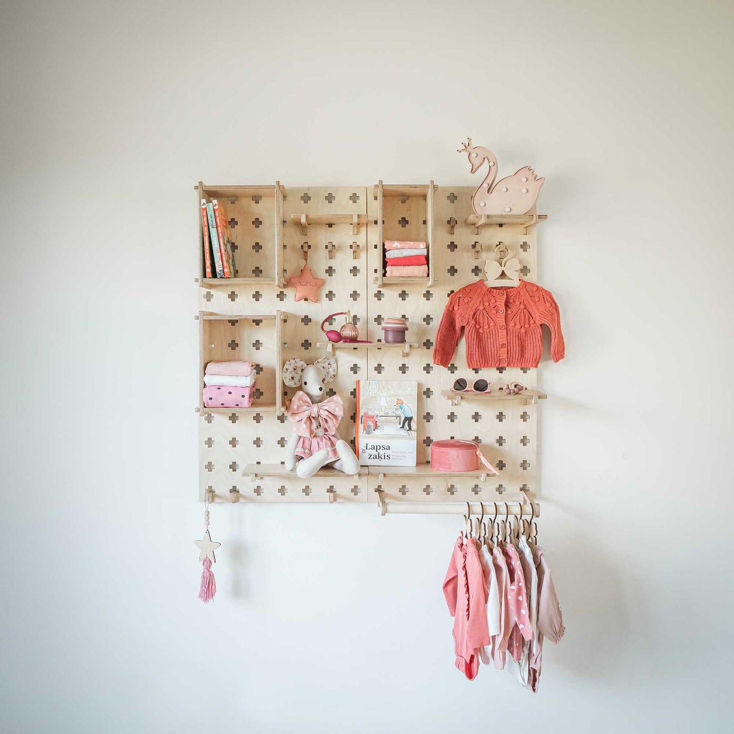 A Large Pegboard Shelf with Clothes Hanger from Sweet HOME from wood, with clothes and toys hanging on it.