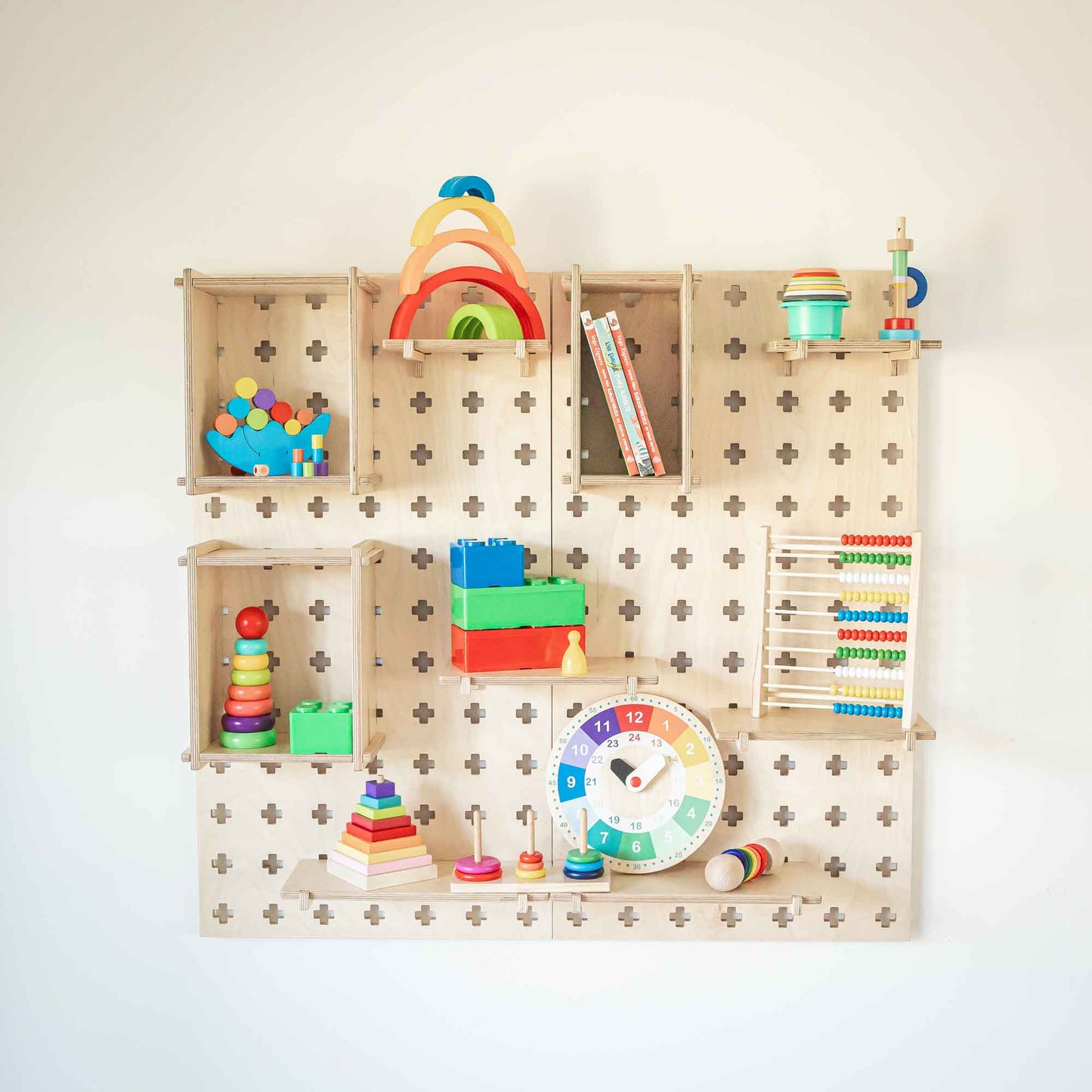 The Large Pegboard Display Stand, adorned with colorful children's educational toys like a clock, abacus, stackable rings, and geometric shape blocks, provides a bright and engaging storage solution that is perfect for decluttering any playroom.