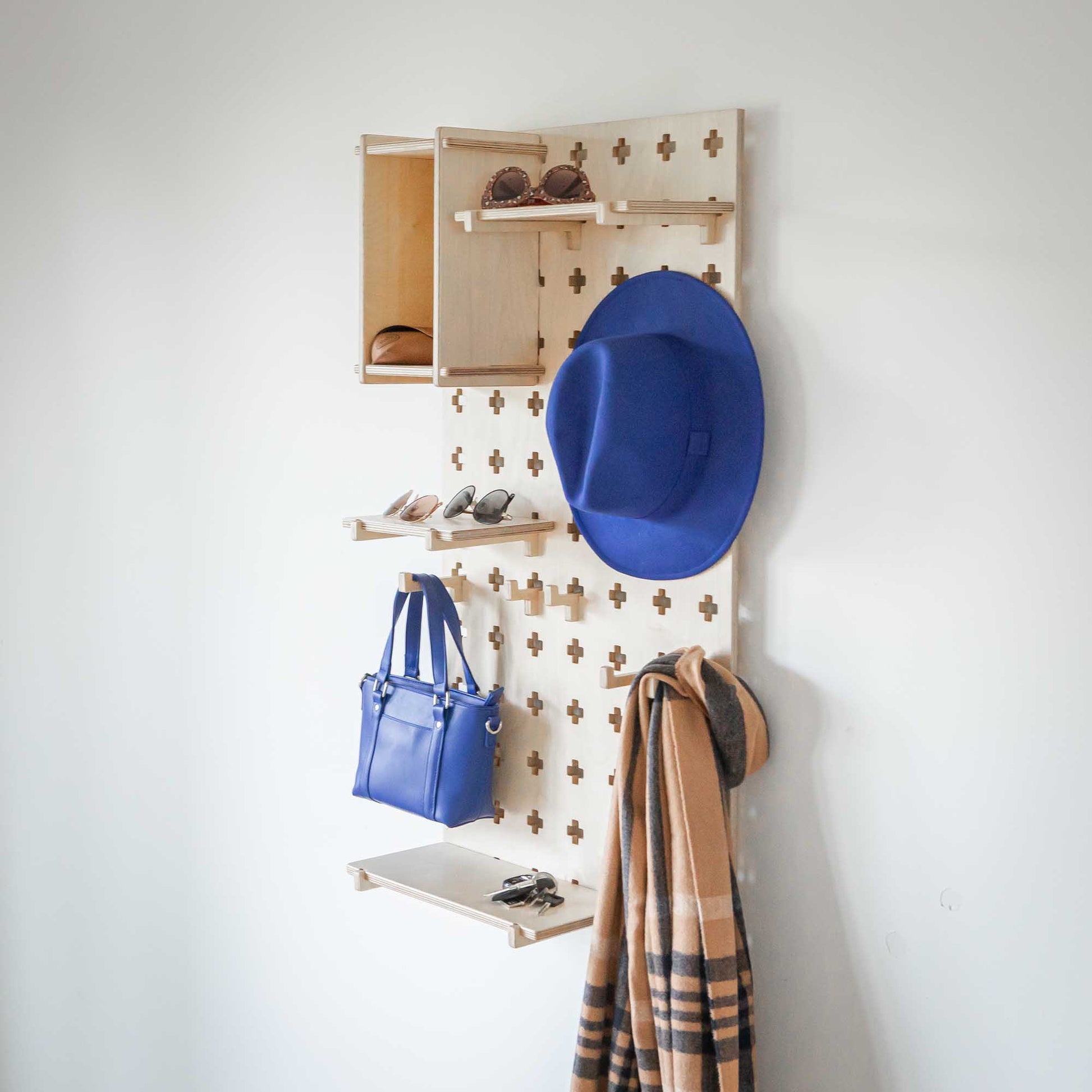 A "Sweet HOME from wood" Floating Shelves Pegboard with hats and bags hanging on it, providing open storage shelves for all your organizational needs.
