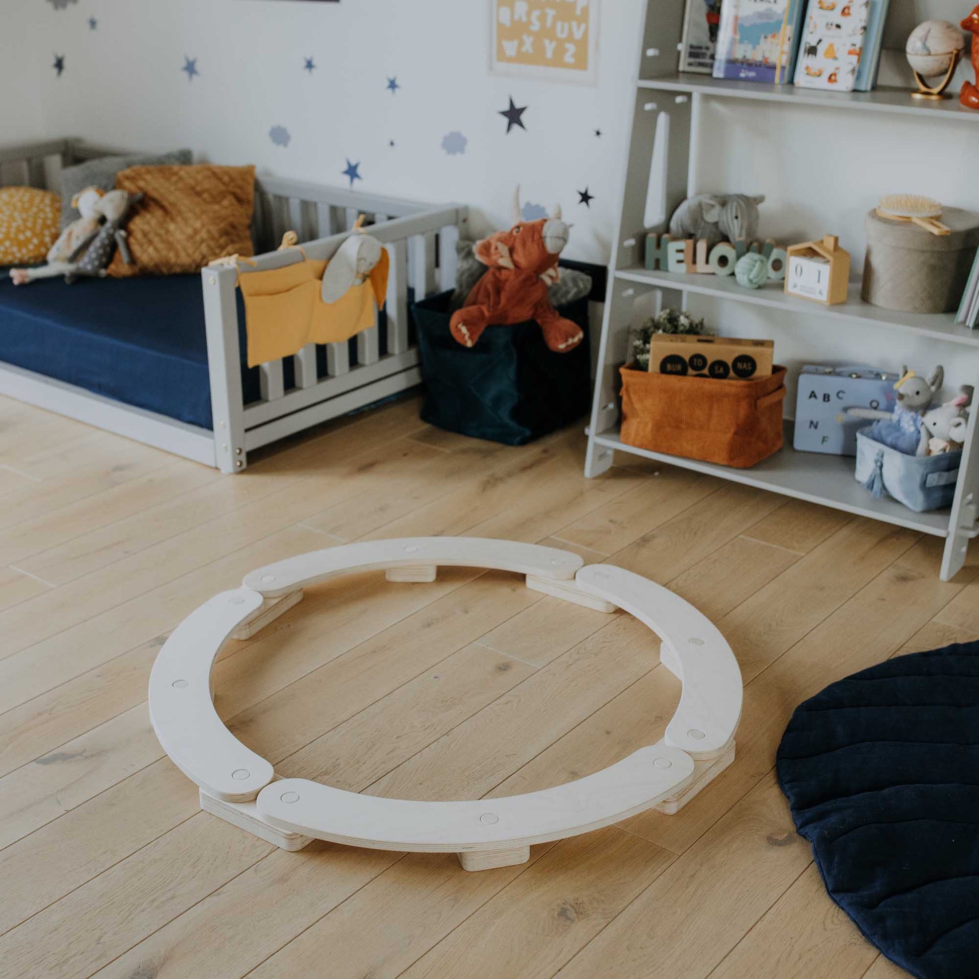 A Montessori toy set up in a child's room with Round balance beams and a circle play mat.