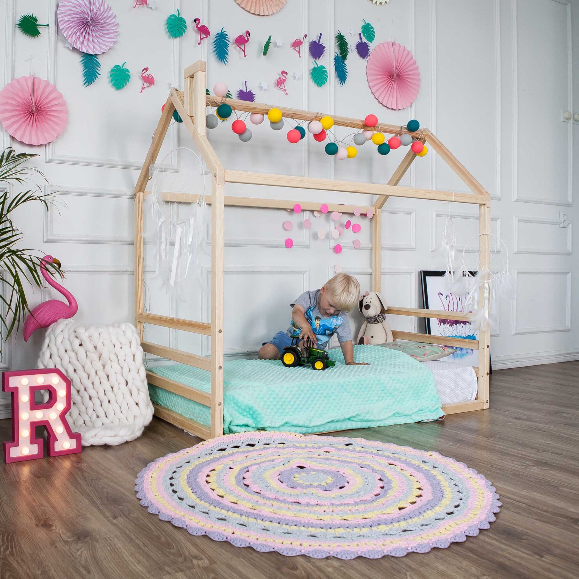 A child's room with a floor house-frame bed with a horizontal headboard and footboard.