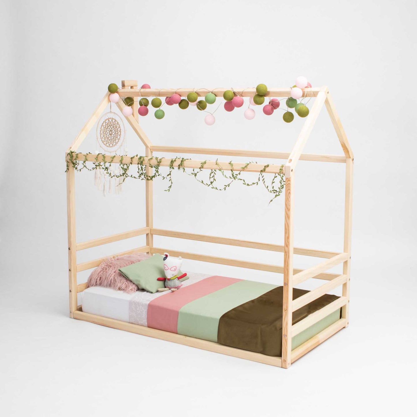 A Kids' house-frame bed with 3-sided horizontal rails with a pink and green canopy.