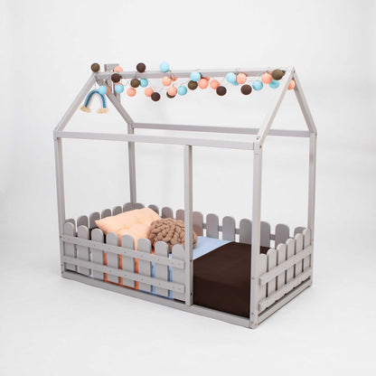 A platform house bed with a picket fence with a baby in it.