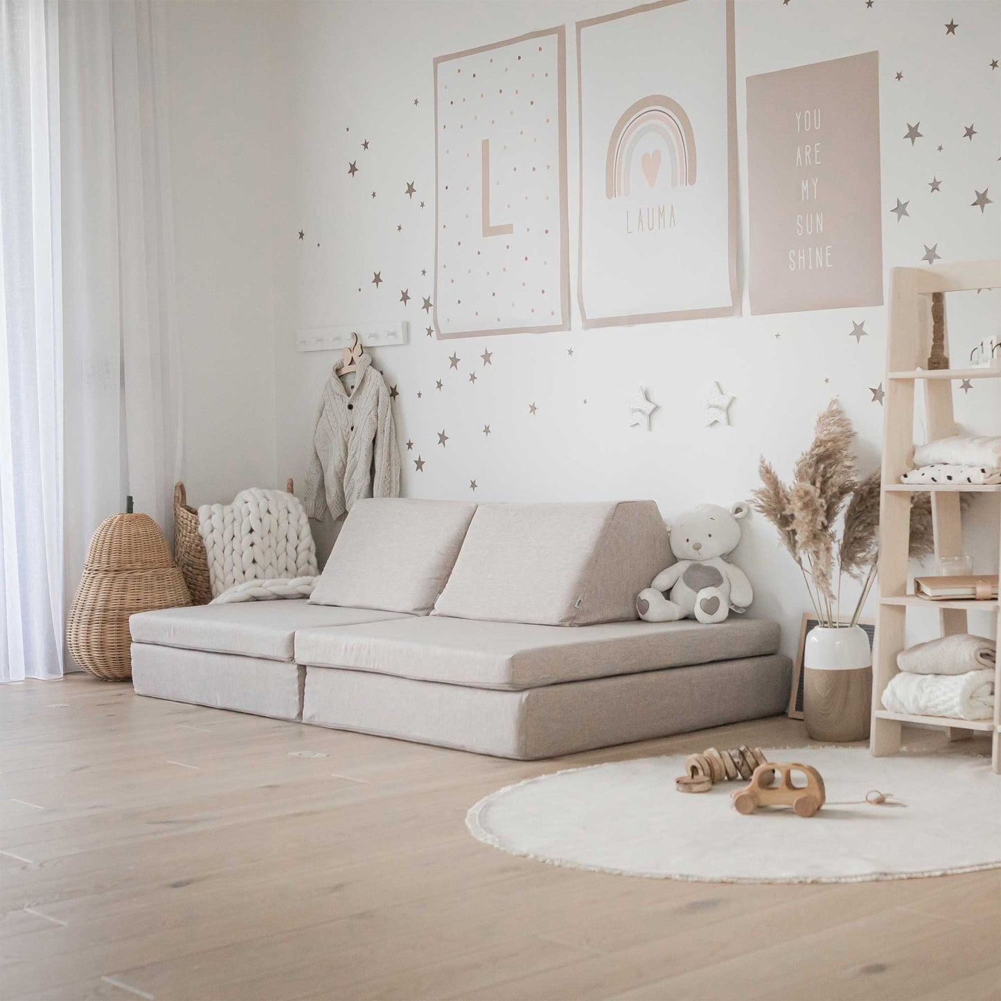 A child's room with a white couch and wooden floor, featuring a Sweet HOME from wood Activity play couch set for kids.