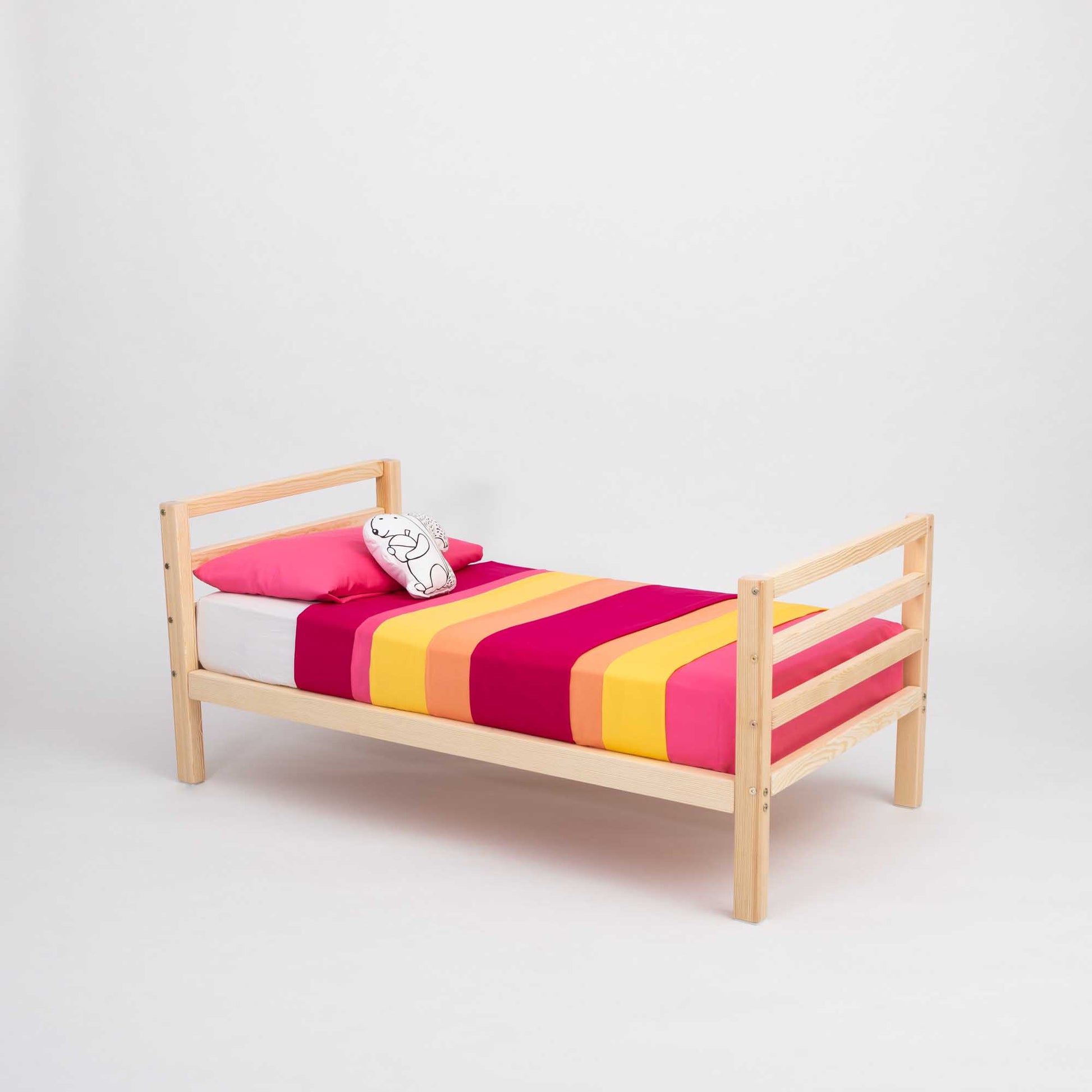 A Sweet Home From Wood kids' bed on legs with a horizontal rail headboard and footboard, with a pink and yellow striped blanket.