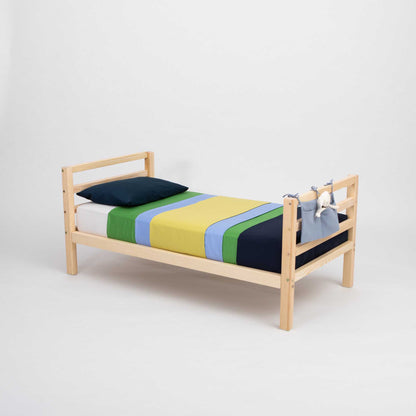 A long-lasting 2-in-1 kids' bed with a horizontal rail headboard and footboard that grows with the child, featuring a wooden frame and a colorful striped sheet, from Sweet Home From Wood.