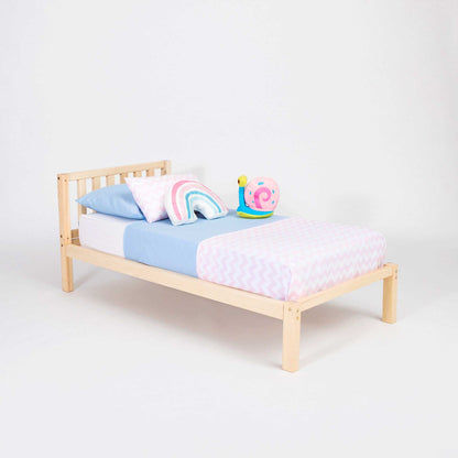 A Sweet Home From Wood 2-in-1 toddler bed on legs with a vertical rail headboard with a pink and blue pillow on it.