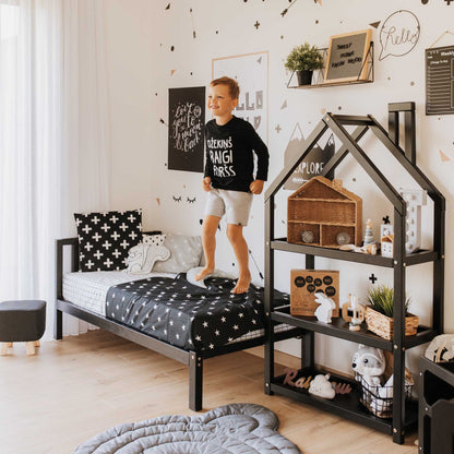A Montessori-inspired boy's bedroom with a Sweet Home From Wood kids' bed on legs with a headboard, featuring black and white decor to foster independence.