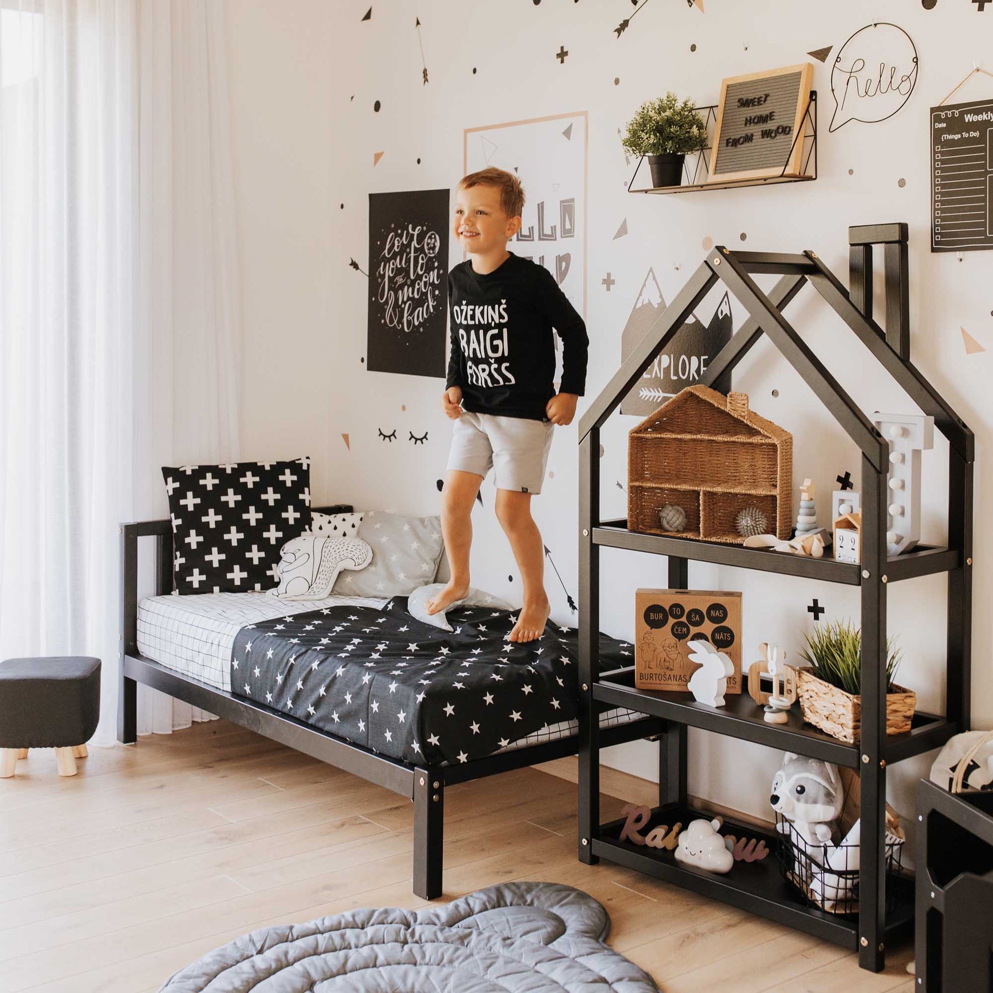 A Sweet Home From Wood 2-in-1 toddler bed on legs with a vertical rail headboard in a Montessori-inspired boy's bedroom with black and white decor.