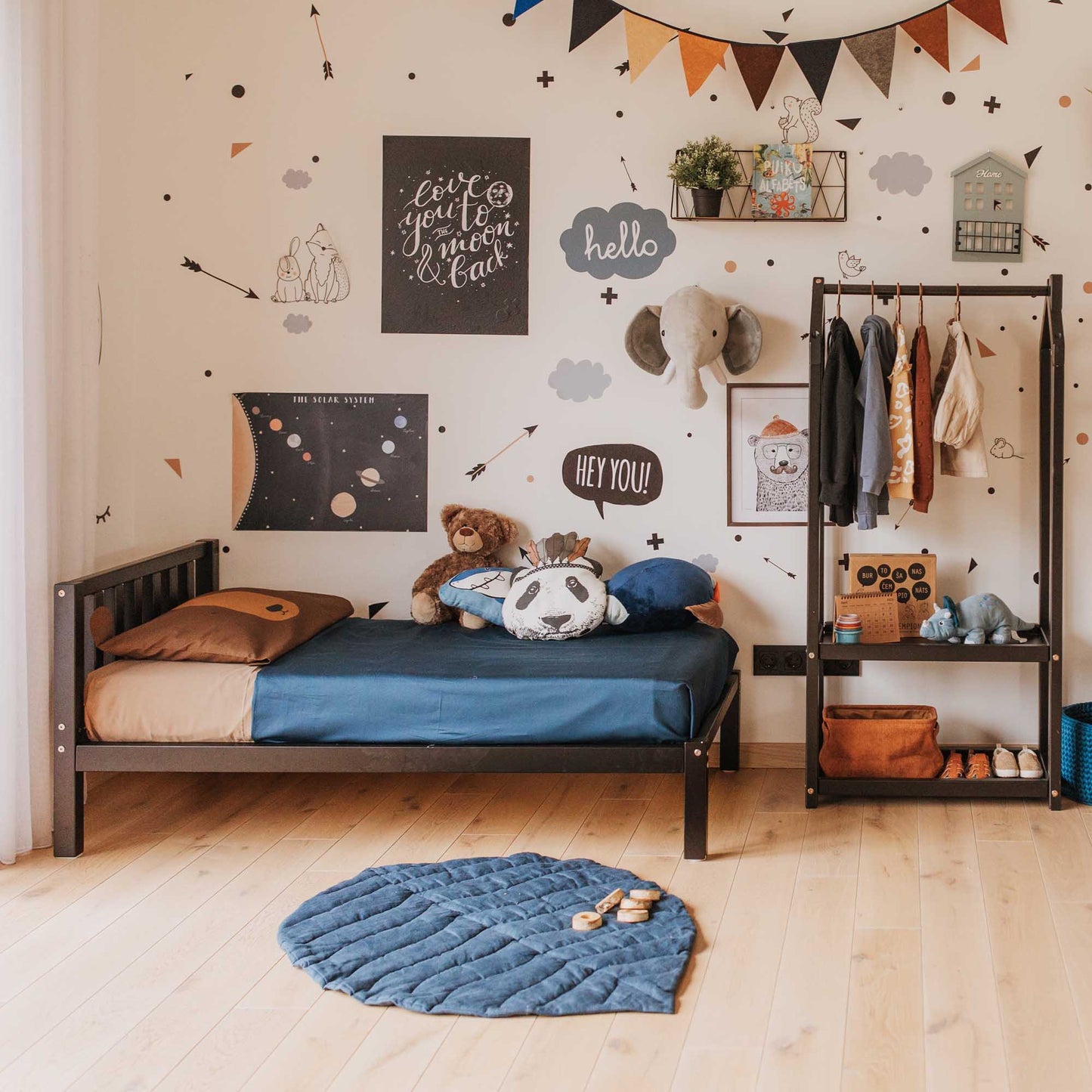 A boy's room with a Sweet Home From Wood 2-in-1 toddler bed on legs with a vertical rail headboard and stuffed animals.