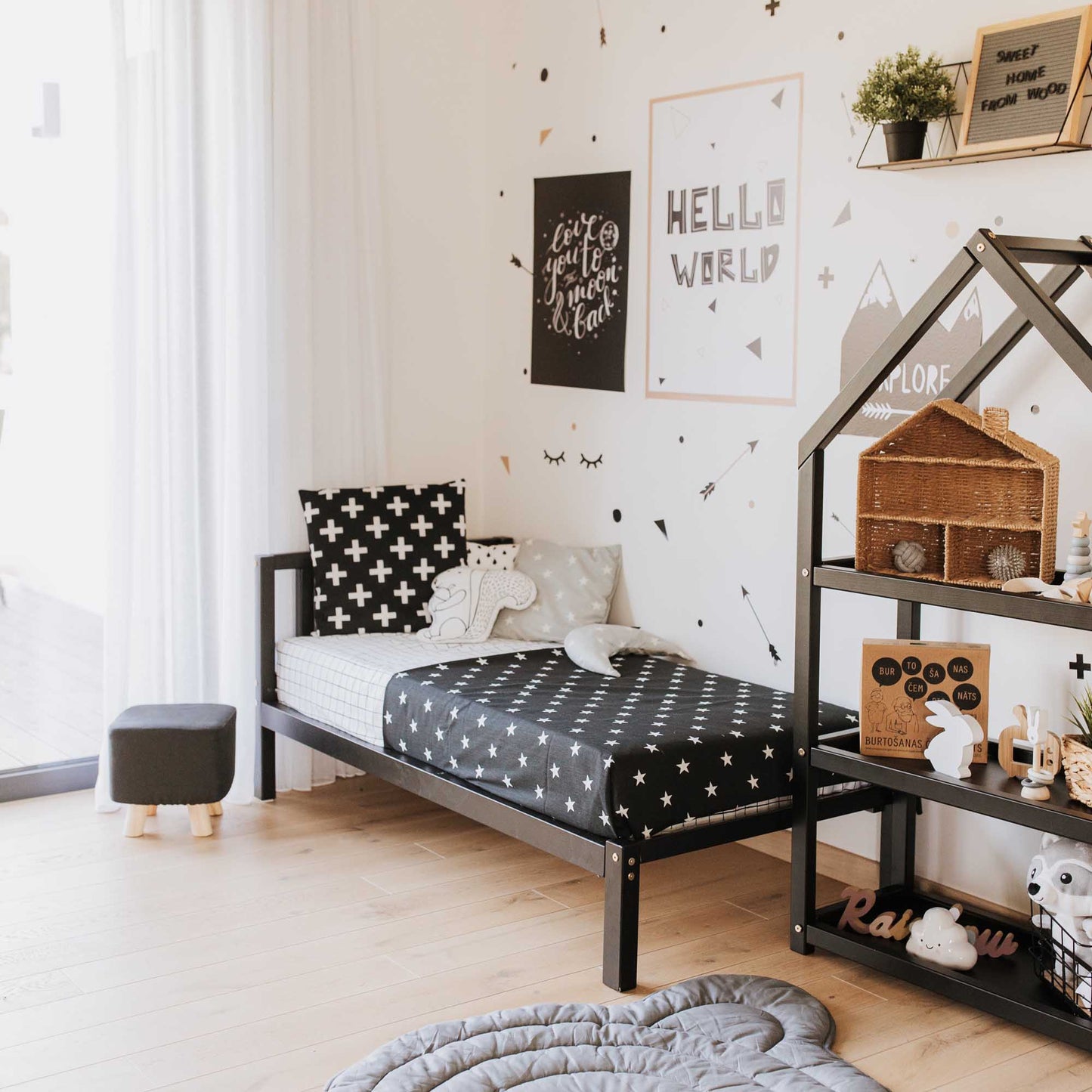 A black and white children's room decorated with polka dots on the walls. The room features a Sweet Home From Wood kids' bed on legs with a headboard, promoting independence in a Montessori-inspired environment.
