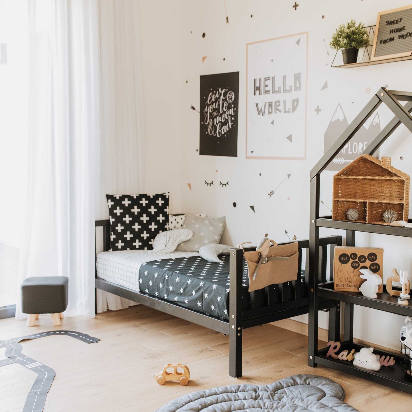 A Montessori-inspired children's room with a Sweet Home From Wood raised kids' bed on legs with a headboard and footboard, and toys, promoting independence.