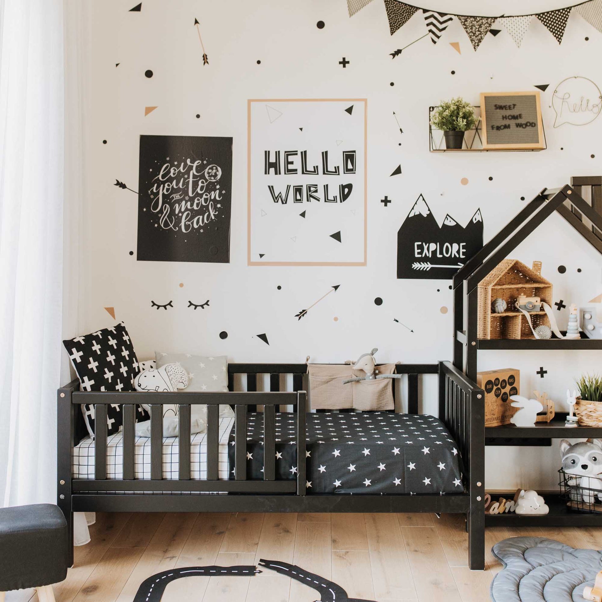 A black and white children's room with polka dots features a Sweet Home From Wood 2-in-1 toddler bed on legs with a vertical rail fence.