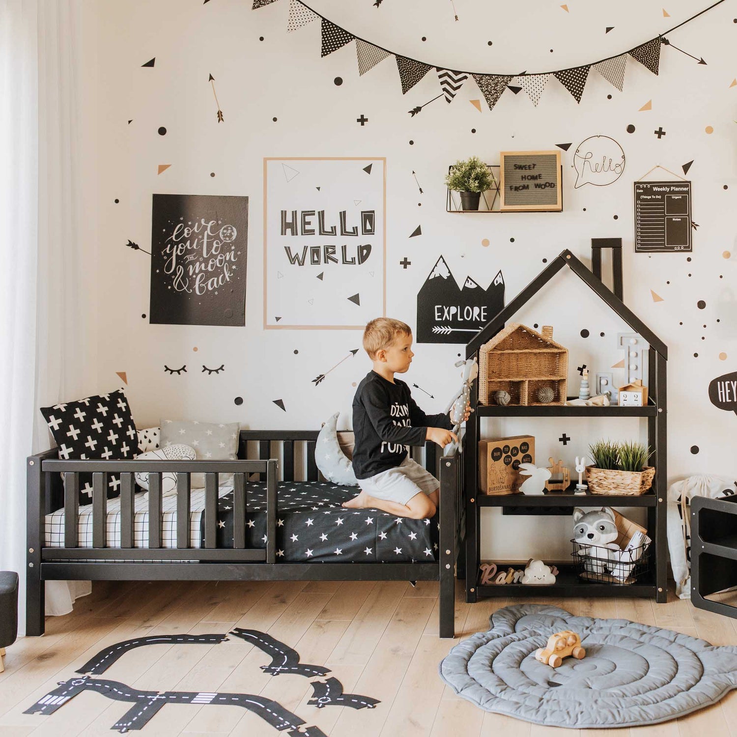A black and white boy's room with polka dots featuring the Sweet Home From Wood 2-in-1 toddler bed on legs with a vertical rail fence.