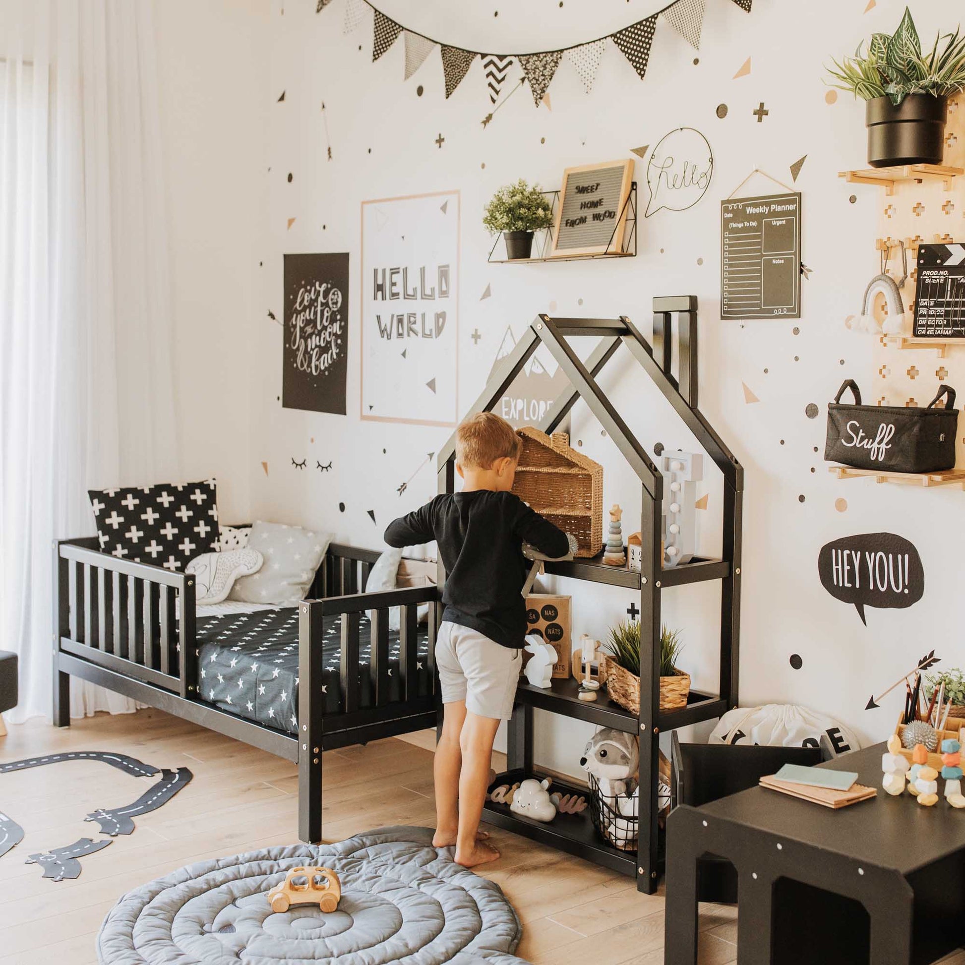 A long-lasting Sweet Home From Wood 2-in-1 toddler bed on legs with a vertical rail fence in a boy's room decorated with black and white polka dots.
