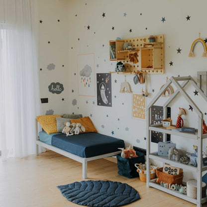 A toddler's room with a Sweet Home From Wood 2-in-1 toddler bed on legs with a vertical rail headboard and a star wall.