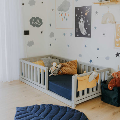 A child's room with a Sweet Home From Wood 2-in-1 toddler bed on legs with a vertical rail fence and a blue rug.