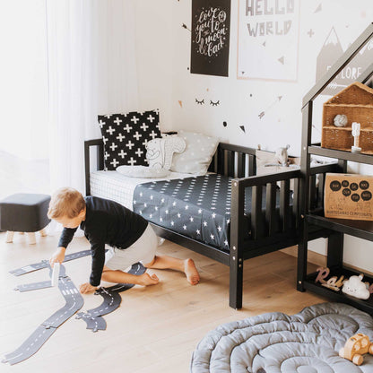 Montessori furniture-inspired children's room with a toddler bed on legs, equipped with safety rails, complemented by a cozy rug for a warm and inviting space.