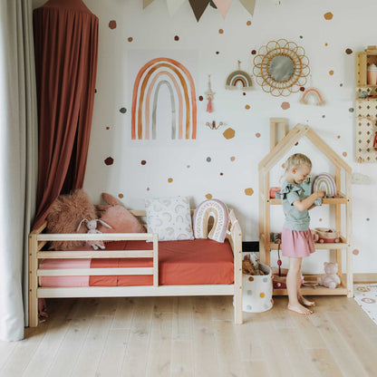 A little girl's room with a Sweet Home From Wood 2-in-1 transformable kids' bed with a horizontal rail fence and polka dot walls.