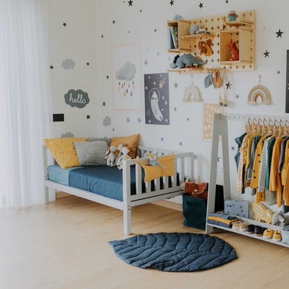 A Montessori-inspired child's room with yellow, blue, and white decorations featuring a Sweet Home From Wood kids' platform bed on legs with 3-sided rails made of solid wood.