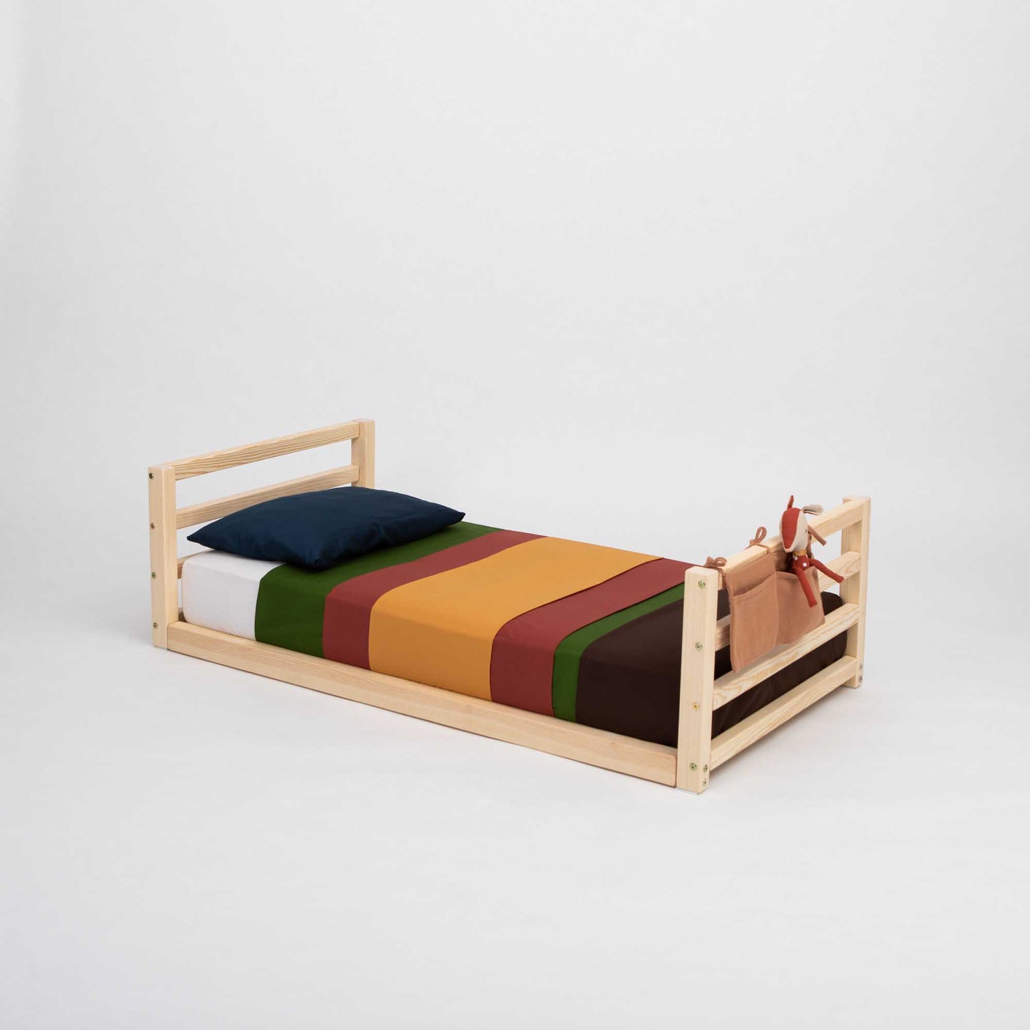 A Sweet Home From Wood Toddler floor bed with a horizontal rail headboard and footboard, with a colorful striped blanket for kids.