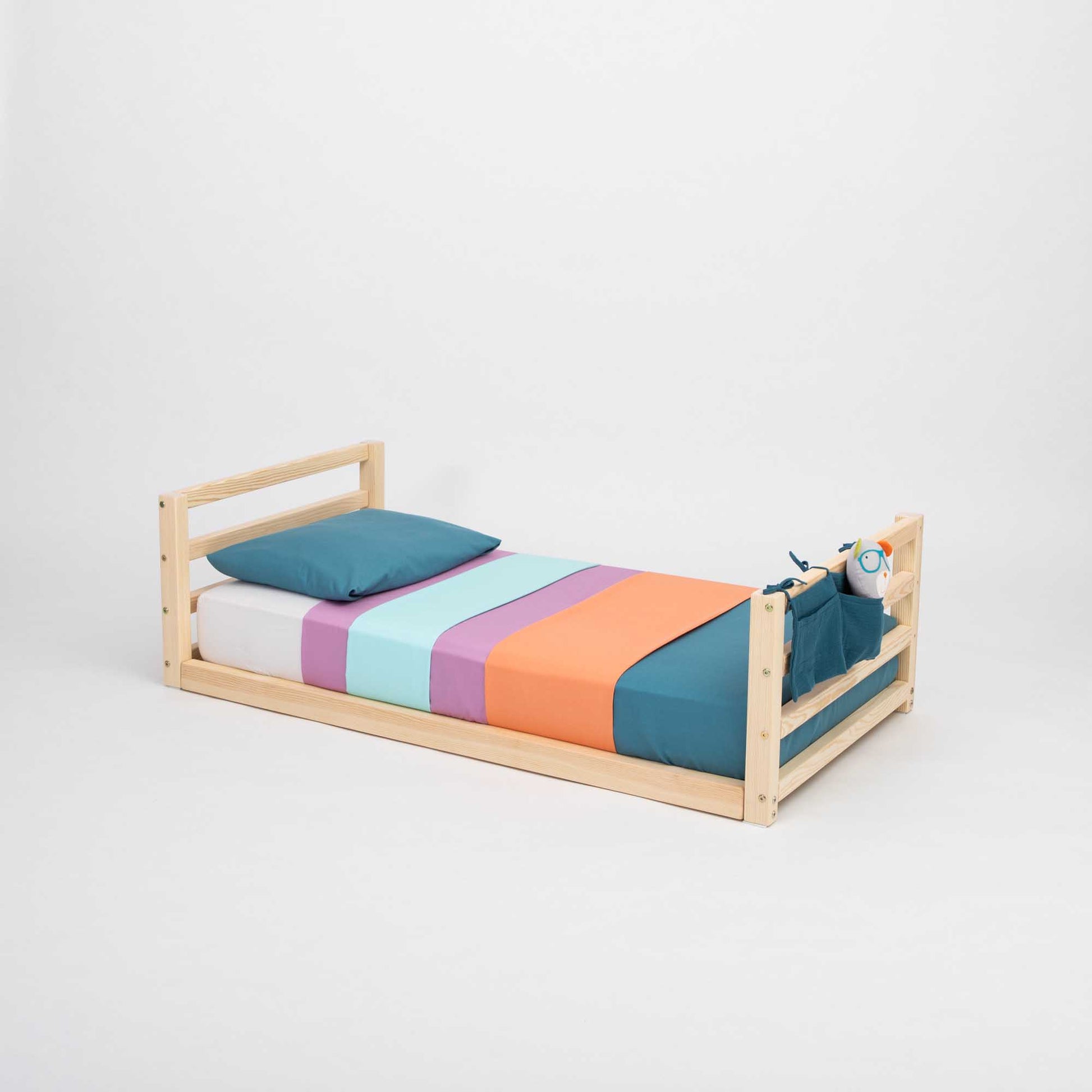 A long-lasting 2-in-1 kids' bed with a horizontal rail headboard and footboard, featuring colorful sheets and a wooden frame, from Sweet Home From Wood.