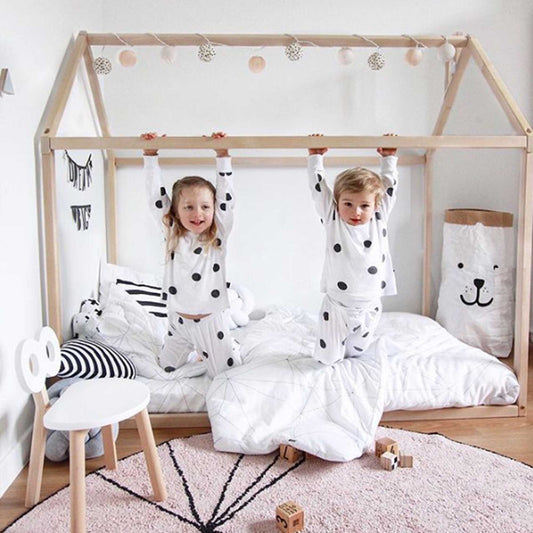 Two kids in polka dot pajamas enjoy a cozy sleep haven in a Sweet Home From Wood Wooden zero-clearance house bed.