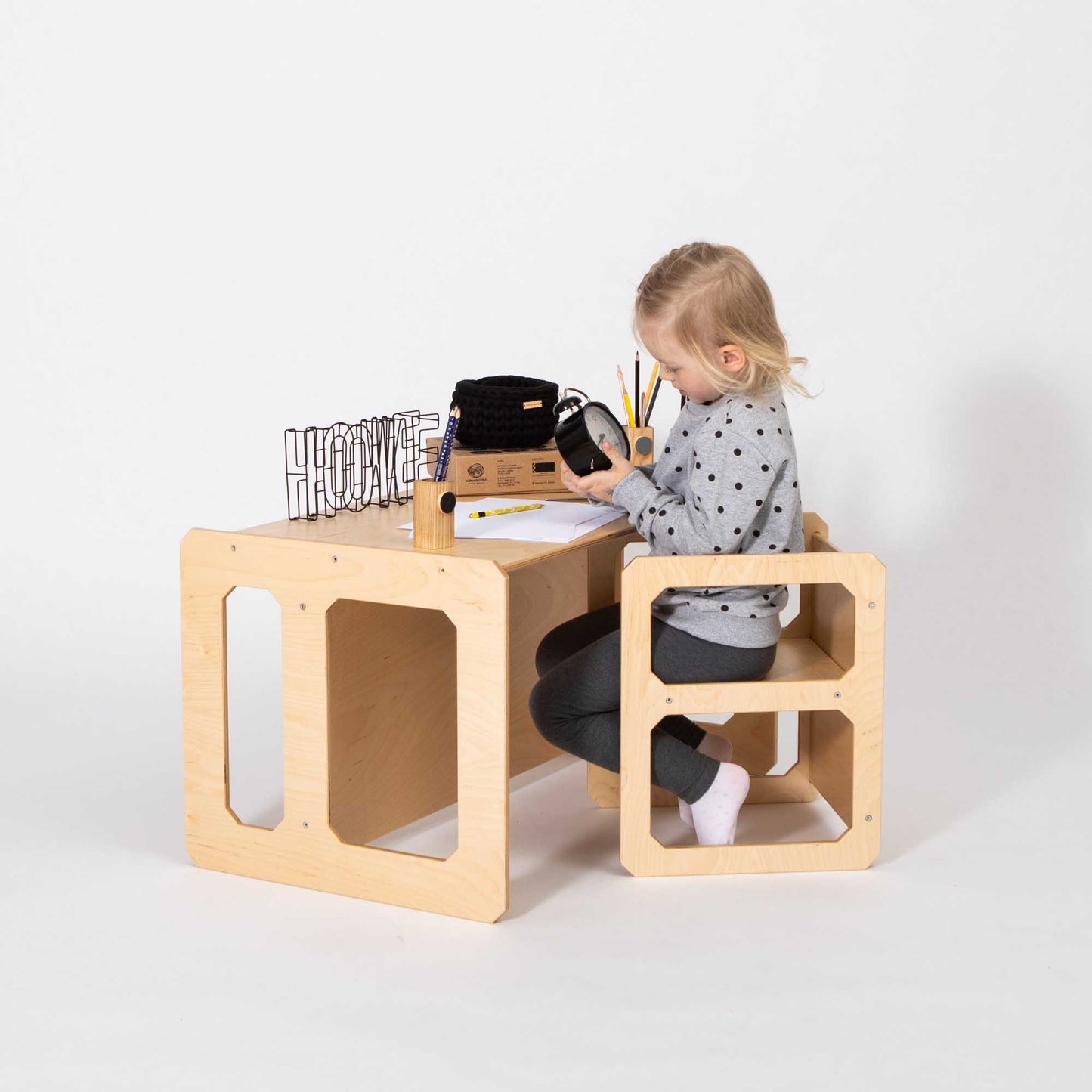 A little girl sitting at a Montessori weaning table and chair set by Sweet Home From Wood.