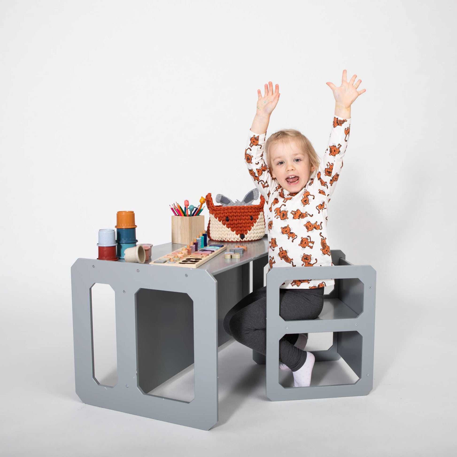 A young child sitting on a Sweet Home From Wood Montessori weaning table and chair set.
