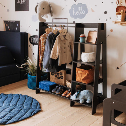 A child's room with a black ladder and a blue rug featuring a Sweet Home From Wood Children's wardrobe, dress up clothing rack.