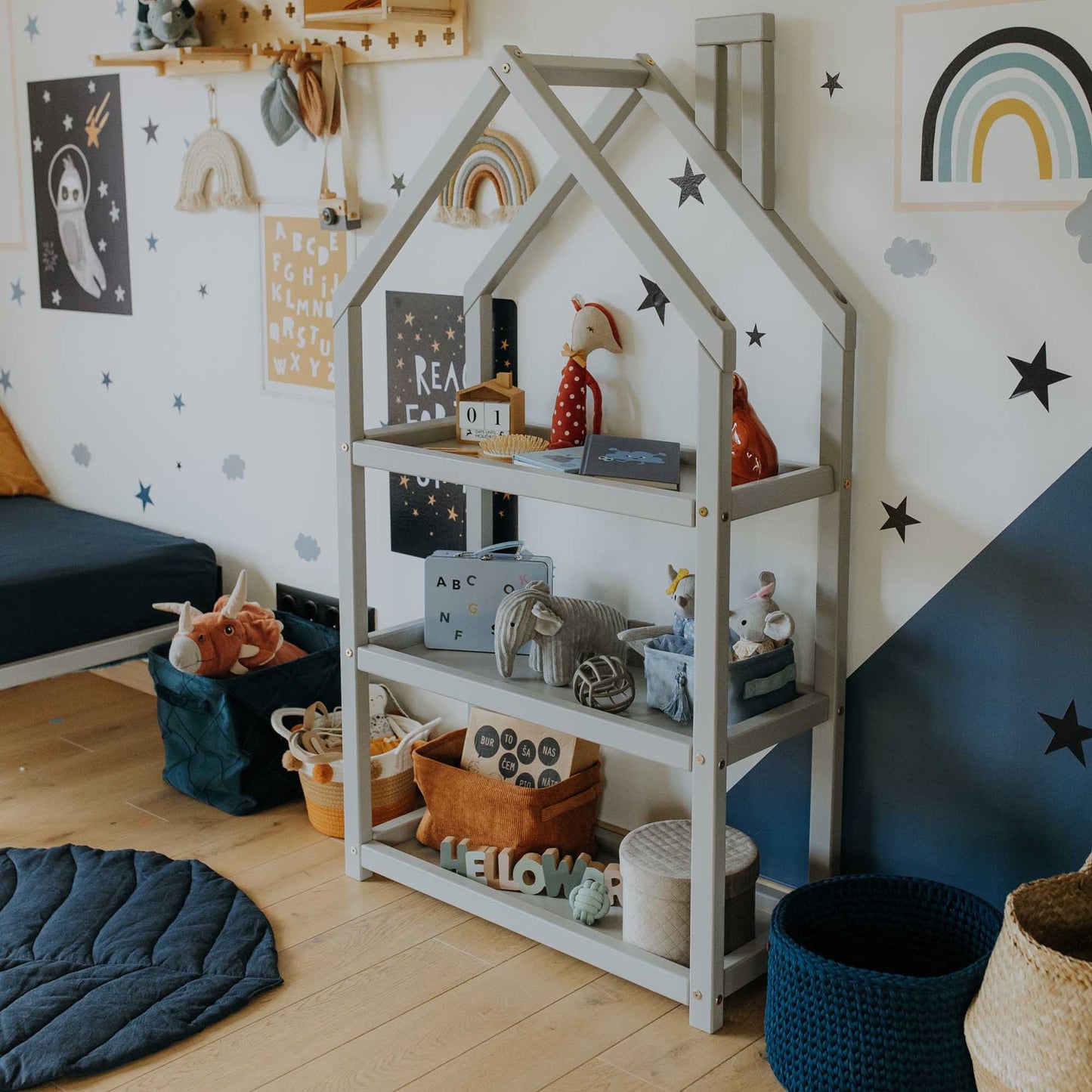 A child's room with a House-shaped Montessori shelf from Sweet Home From Wood and stars on the wall.